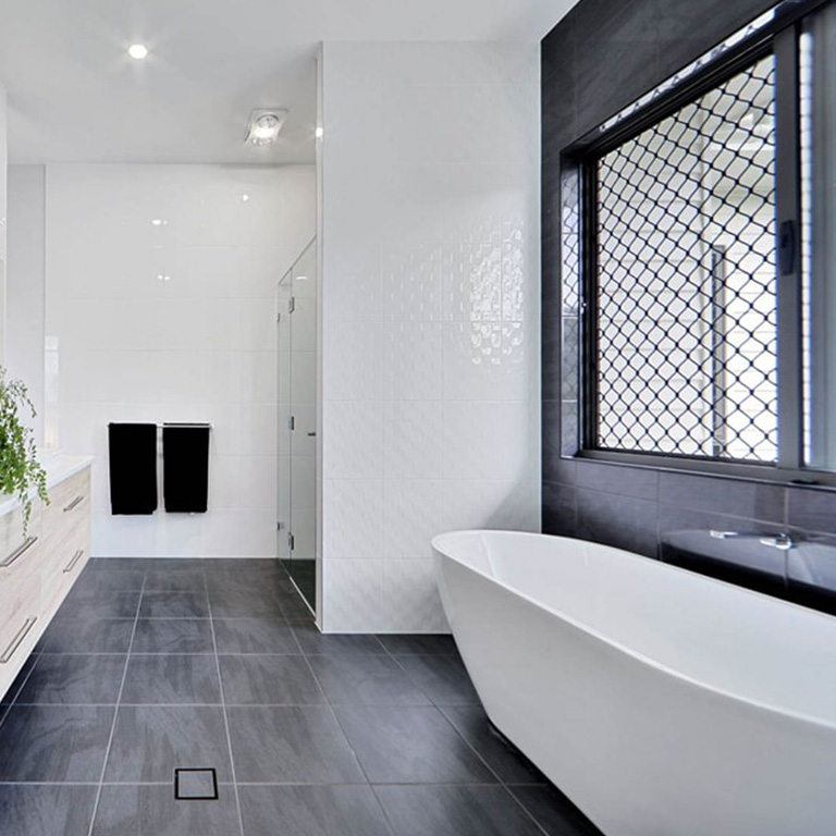 Bathroom with freestanding bath, dark floor tiles and white feature wall tiles