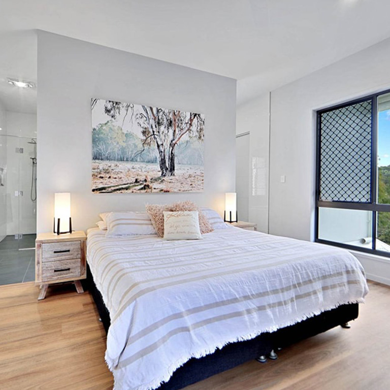Bedroom with striped bedspread, timber floors and gum tree artwork