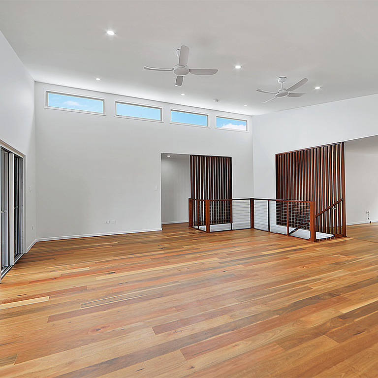 Spacious living room with timber floors, ceiling fans and high windows
