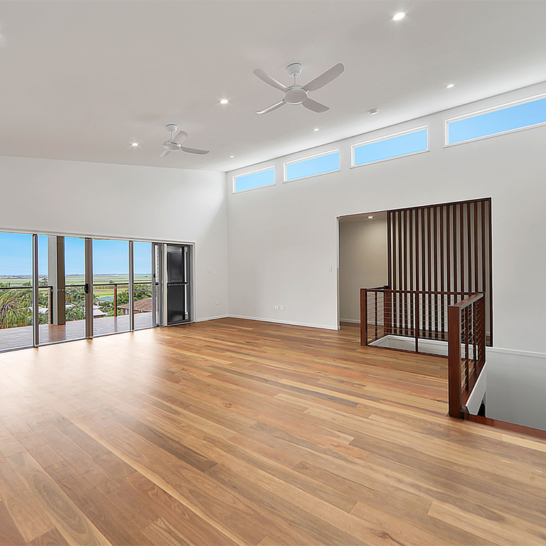 Timber-floored living room with slatted stair screen and sliding doors to a view