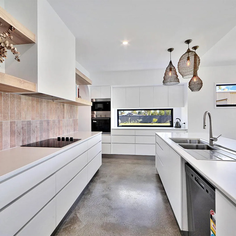 White kitchen with pink tile splashback, woven pendant lights and concrete floor